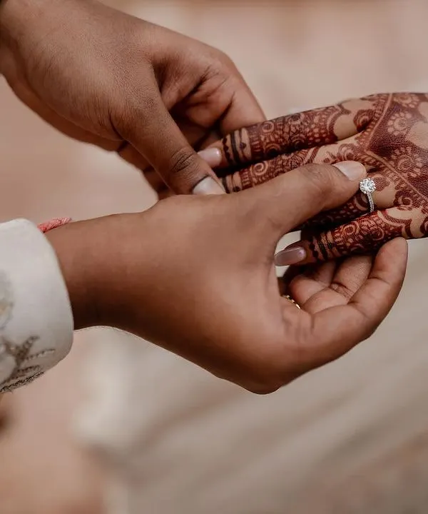 A close-up of the ring exchange, a symbol of commitment. We focus on capturing these crucial details, including the intricate henna designs that tell their own story.
