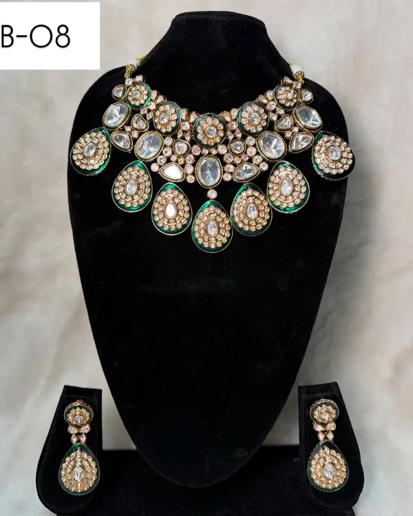 My bridal set B-08 is a bold choker featuring large, teardrop-shaped polki stones with green meenakari work. The matching earrings complete this regal rental set.