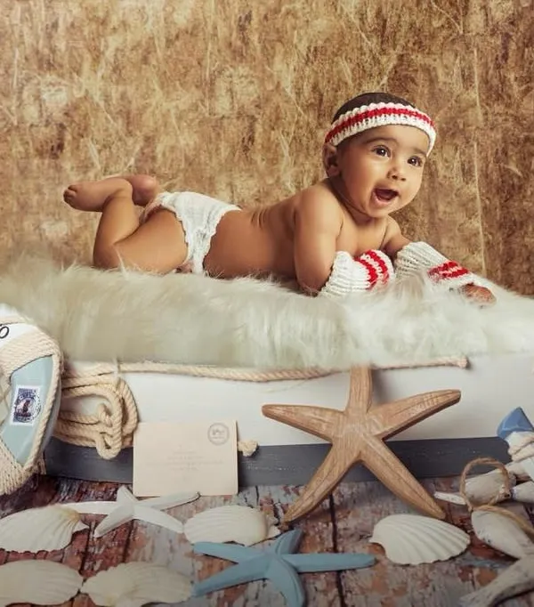 This little sailor is ready for an adventure. A 6-month sitter session is the perfect time to use fun themes like this nautical setup, complete with a lifebuoy, starfish, and an anchor. His excited expression shows off his budding personality.