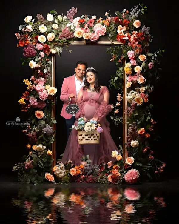 A living portrait, framed in flowers. This elaborate floral setup creates a breathtaking, artistic announcement. The reflection adds a layer of depth, making it a truly magical and memorable image.