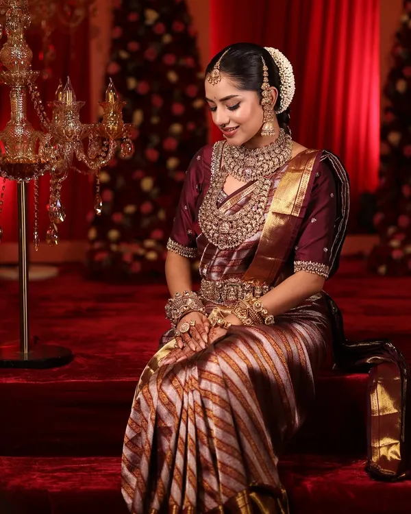 A demure pose from a South Indian bride, showing the rich texture of her Kanjeevaram saree and layered necklaces.