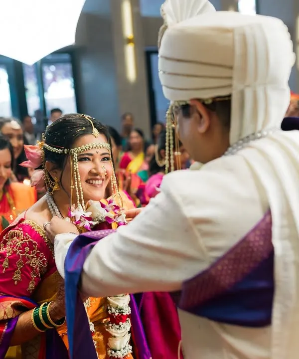 A key moment in a Maharashtrian wedding, the Varmala exchange. The bride's smile says it all as friends and family cheer them on.