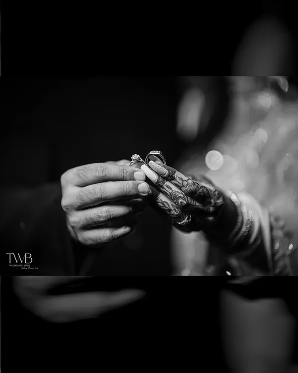 A powerful black and white shot of the ring exchange. This close-up focuses on the hands and the ring, symbolizing the promise and commitment at the heart of the ceremony.