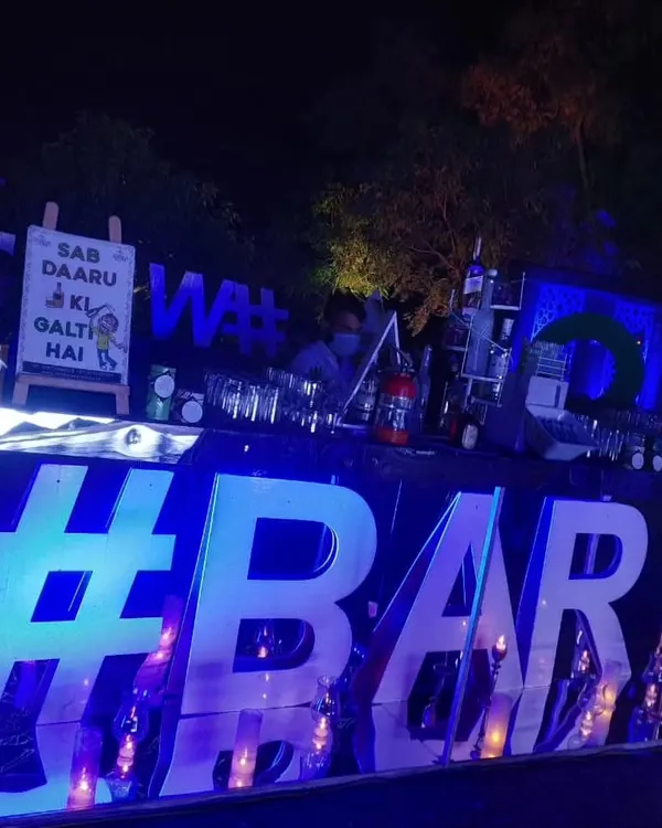 This modern bar setup is one of my most popular for evening parties. The large, blue-lit '#BAR' sign creates a striking focal point, while the humorous chalkboard sign adds a personal, lighthearted touch.