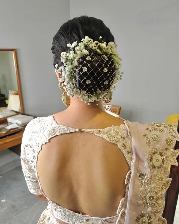 A classic bridal bun adorned with a net of baby's breath flowers. This is a delicate and romantic choice, perfect for a bride who loves a soft, ethereal look.