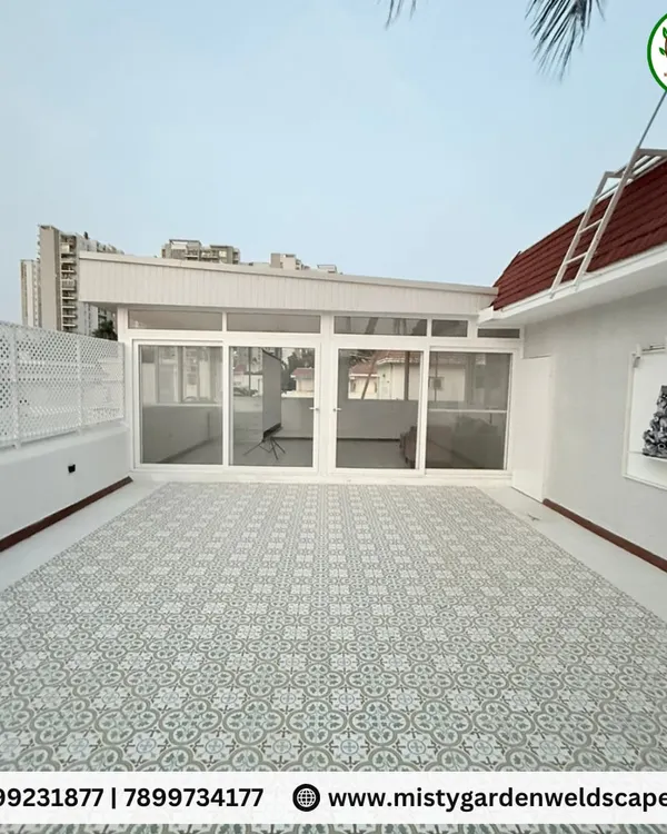 This is the exterior of a completed terrace room at Skylark Greens. It features a durable PUF sheet roof, UPVC sliding doors, and a PVC lattice privacy screen, all in a clean white finish that brightens the space.