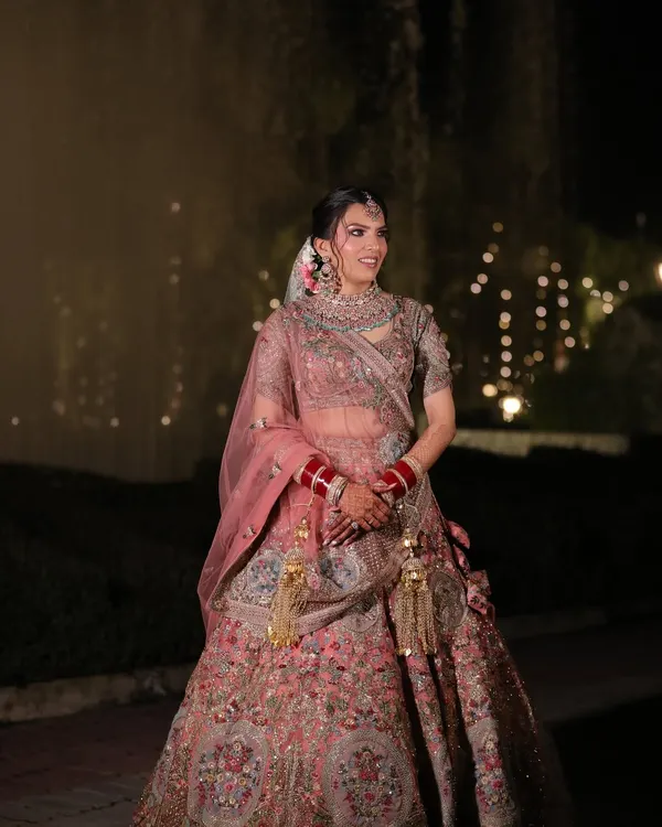 A full view of Muskaan's stunning pastel pink lehenga. The makeup was designed to be soft and romantic, with pink hues on the eyes and lips to create a cohesive, modern bridal look.