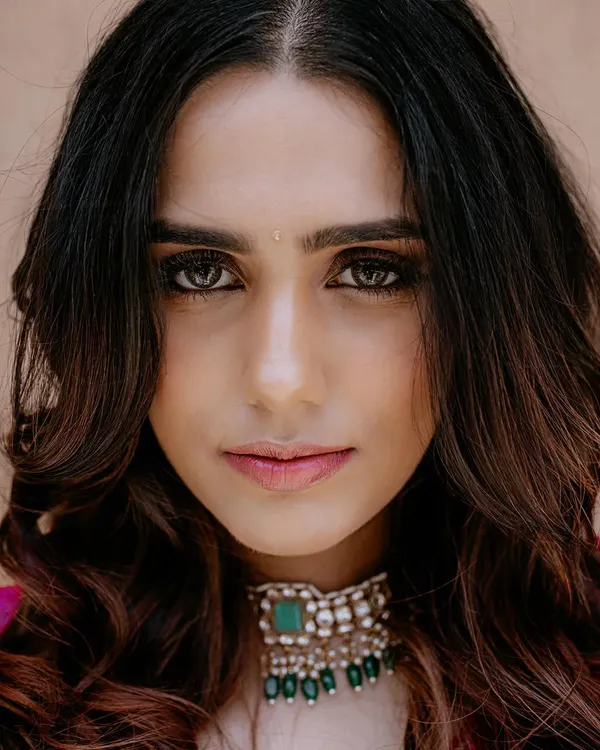 A stunning close-up bridal portrait. The direct gaze, flawless makeup, and intricate choker necklace are the focus of this beautiful shot.