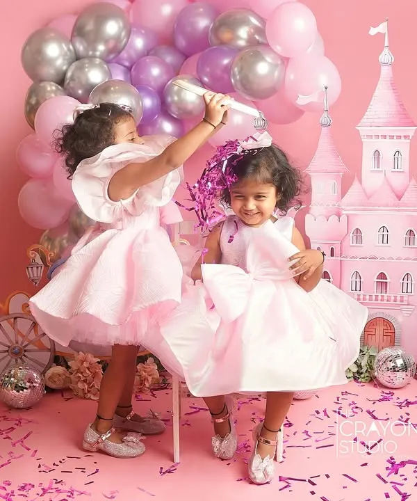 A shower of confetti in a pink princess castle. This action shot captures the pure, uninhibited joy of two sisters celebrating in a world we created just for them in the studio.