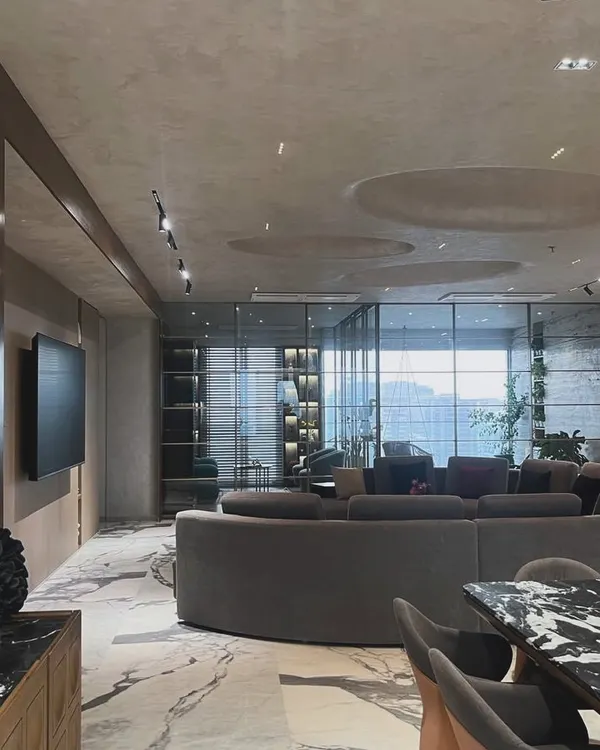 The open-plan living area in this modern apartment is defined by its curved sofa and dramatic marble flooring. We designed the space to feel both expansive and intimate, with recessed ceiling details and track lighting to highlight specific zones.