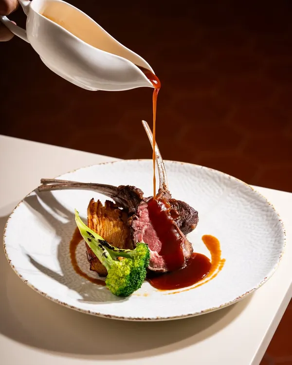A perfect pour of rich jus over tender lamb chops. I focus on capturing these elegant, mouth-watering moments that elevate a dish from food to art.