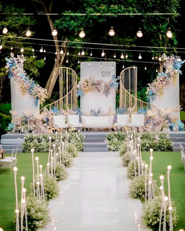 We created a dreamlike atmosphere for this outdoor wedding with a magnificent all-white stage. The elegant arches, pastel floral arrangements, and softly lit aisle created a truly romantic and sophisticated setting for the couple to say "I do".