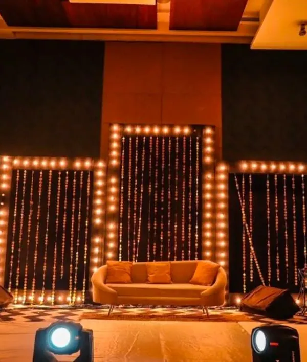This stage design uses a series of panels framed with warm marquee bulbs and string light curtains to create a visually stunning backdrop. It's a versatile setup, ideal for a panel discussion, musical performance, or as a main stage for a company celebration.