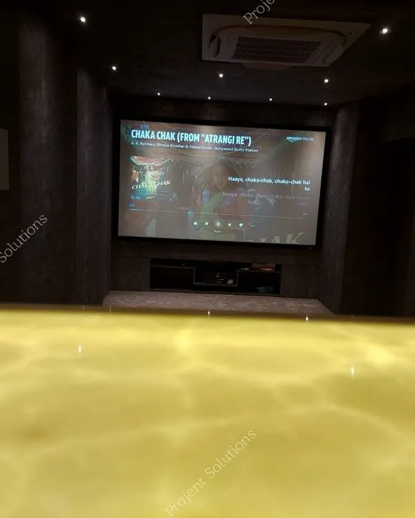 A view from the back of the room, emphasizing the scale of the fixed projector screen. Our installations ensure a bright, sharp 4K image that fills your field of view for a truly immersive experience.