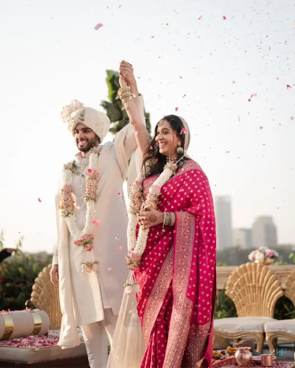 A moment of pure triumph and happiness as the couple celebrates their union under a shower of petals during their golden hour wedding ceremony.