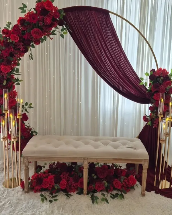 A romantic and elegant stage setup perfect for a ring ceremony or reception. This design features a circular arch with rich red roses, draped fabric, and tall candle stands for a warm, intimate glow.