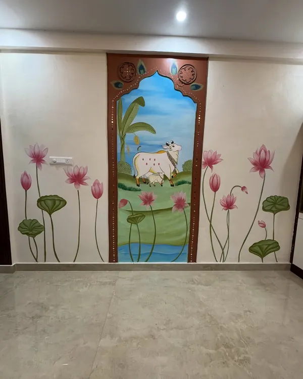 A full view of our Pichwai-inspired wall art. The central panel features a cow and calf, created in relief, while the surrounding wall is painted with beautiful lotus flowers. The arch is decorated with lippan art using ropes and mirrors.