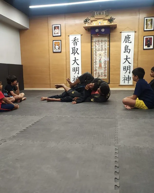 Our kids' jiu-jitsu classes are in full swing. Here, young students watch attentively as our instructor demonstrates a ground position, learning the importance of control and technique from an early age.