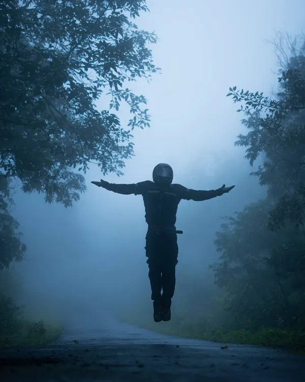 A creative shot of me appearing to levitate on a foggy road, surrounded by mist-covered trees. This image captures the feeling of freedom and breaking away from the mundane that my monsoon rides represent.
