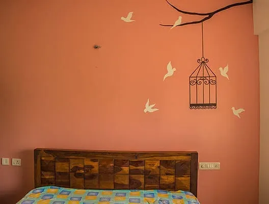 This is the kind of special touch I can add to your home. For this bedroom in Jayanagar, I painted a peaceful nature scene with birds and a branch, making the wall a beautiful piece of art. If you want a unique design, I can create one for you.