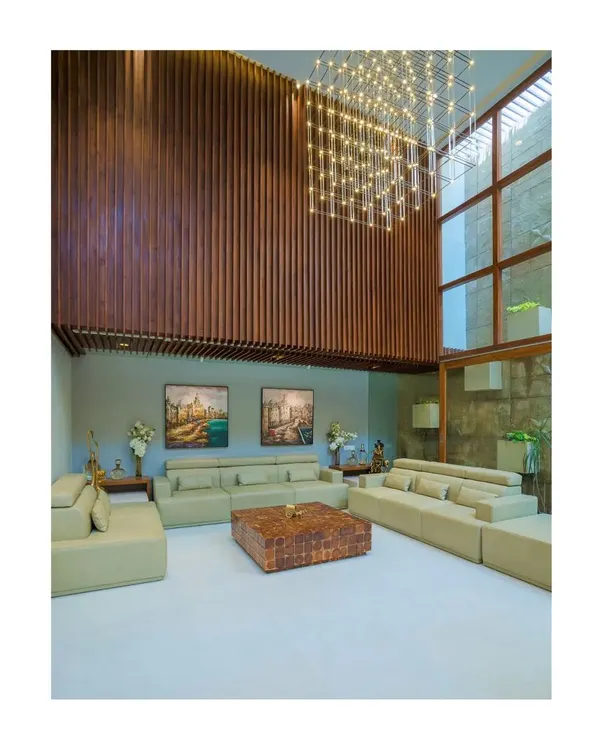 The double-height living area in our Athulyam project is designed to feel grand and airy. We used vertical wood paneling to accentuate the height and a massive, custom chandelier to fill the volume, creating a space that is both impressive and comfortable.