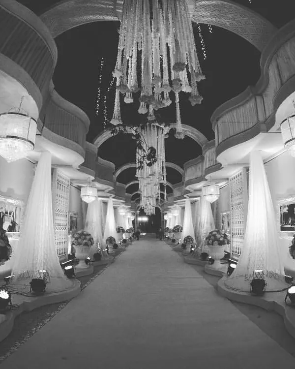 Create a spectacular first impression with a grand, fully decorated walkway. This design uses a series of arches, elegant white drapes, and floral urns to create a luxurious entrance experience.
