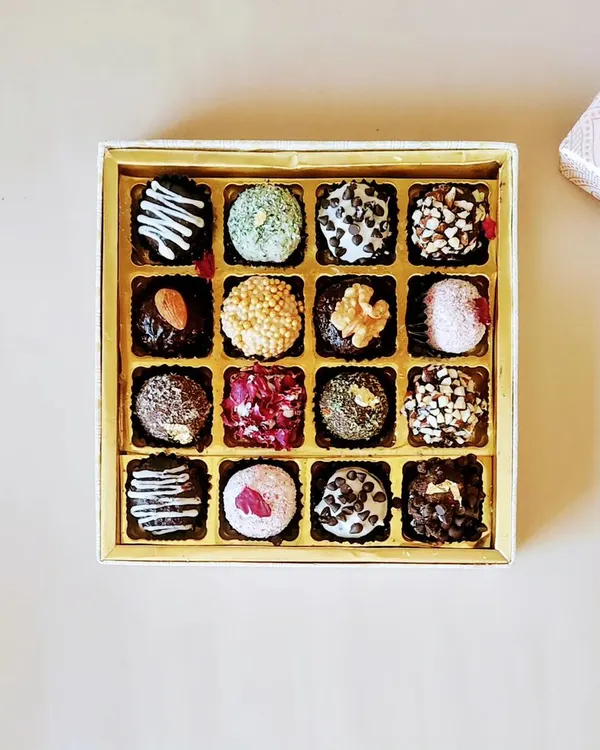 A top down view of our Crunchy Chocolate Truffles box. Each truffle has a different topping, including chocolate chips, chopped nuts, sprinkles, and desiccated coconut for a variety of textures.