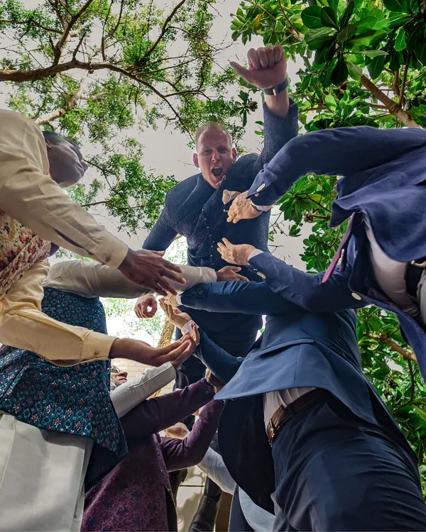A unique, low-angle shot of the groom being lifted by his friends during the baraat. This captures the raw energy and excitement of the celebration from a dynamic perspective.