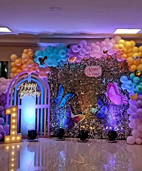 This is a complete butterfly-themed decoration I did for a first birthday party. The setup includes a shimmering silver sequin wall, large 3D butterfly cutouts, a custom marquee number '1', and a neon 'Happy Birthday' sign, creating a magical photo zone for the celebration.