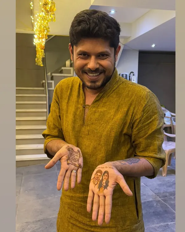 A groom proudly showing his unique mehandi. On one hand, a portrait of his beautiful bride, and on the other, a personal love letter written in henna for her to read.