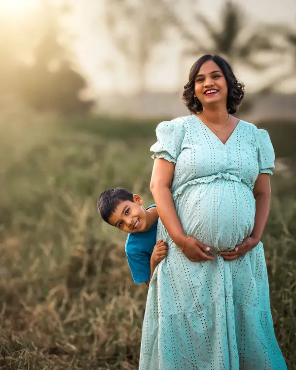 A maternity session is even more special when there's a soon-to-be big brother involved. His playful peek from behind his mother adds a touch of joy and reality to this beautiful moment of anticipation.