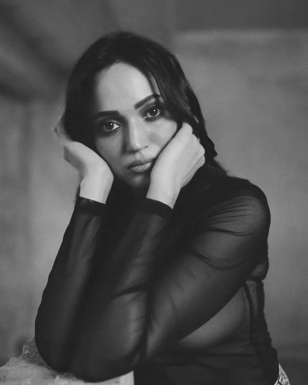 An intimate black and white portrait, where the model's direct gaze and hands framing her face create a powerful, emotional connection.