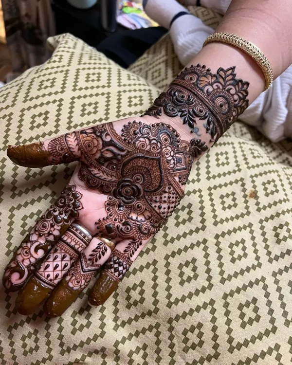 This is my signature bridal mehndi style, featuring a dense and intricate pattern with a central floral mandala, detailed finger work, and a beautiful wrist cuff. I love creating these full-coverage designs that make a bride feel truly special.