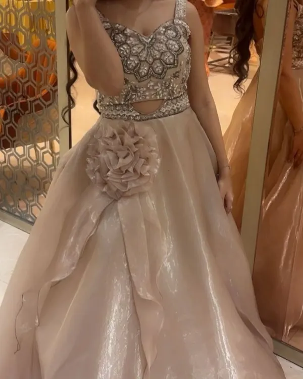 This beige gown is one of my most popular pieces for engagement parties and receptions. It features a heavily embellished bodice with intricate beadwork and a flowing organza skirt with a floral detail.