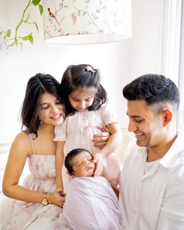 A beautiful black and white portrait of a family welcoming their newborn. The focus is entirely on their expressions of love and happiness, creating a powerful and timeless image.