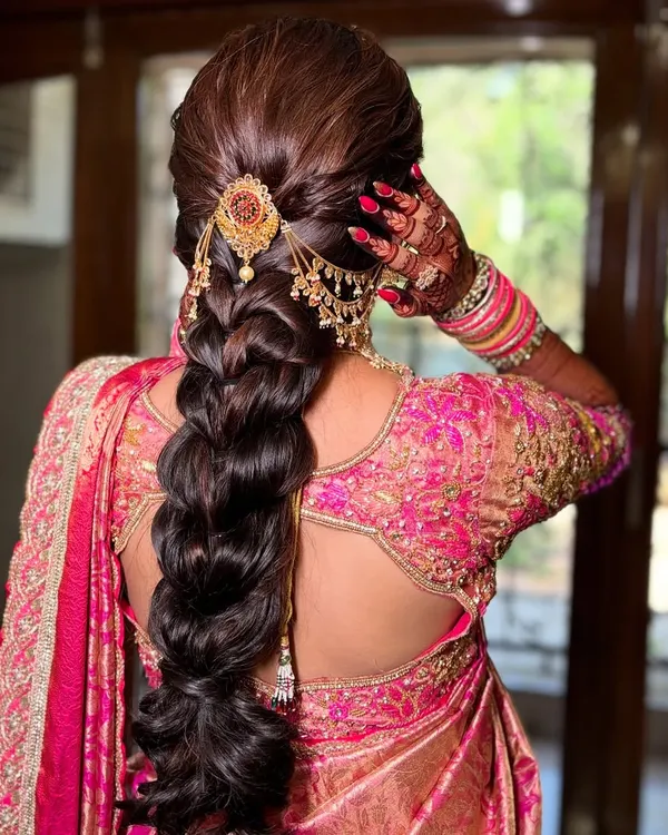 A stunning traditional braid for a Maharashtrian bride. The hairstyle is intricate and elegant, adorned with a beautiful gold accessory.