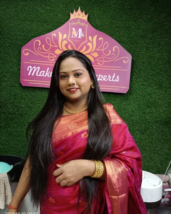 A photo of a happy client at my makeup studio. The green and pink background is a part of my dedicated space for makeovers.