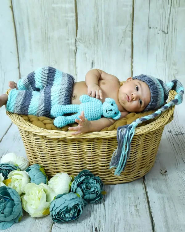 This one-month-old is wide awake and curious. We use cozy props like this wicker basket and handmade outfits for our newborn and infant photoshoots.