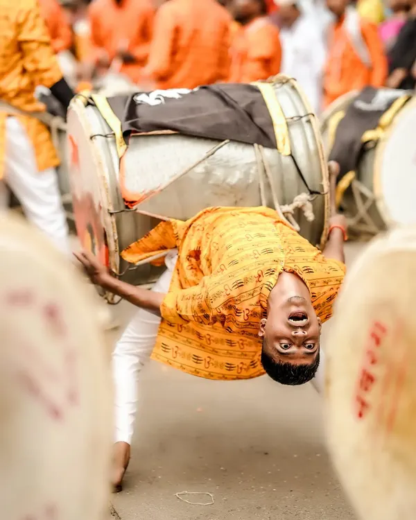 Capturing the peak of energy and devotion. This dynamic shot freezes a dhol player in a moment of acrobatic performance during a street festival.