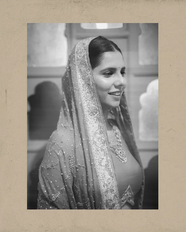 A classic black and white portrait of a bride with her head covered, her gentle smile capturing a moment of timeless grace.
