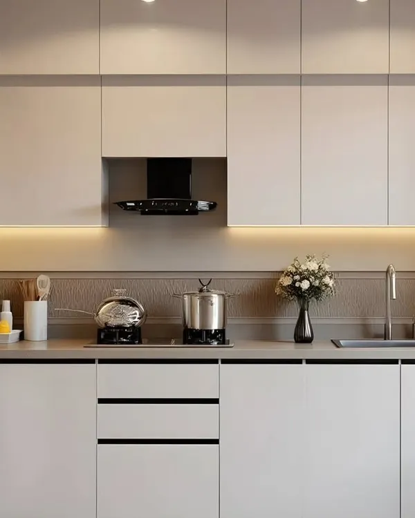 A minimalist parallel kitchen design featuring all-white handle-less cabinets. The warm under-cabinet lighting and textured backsplash add depth and character, proving that simple can be stunning.