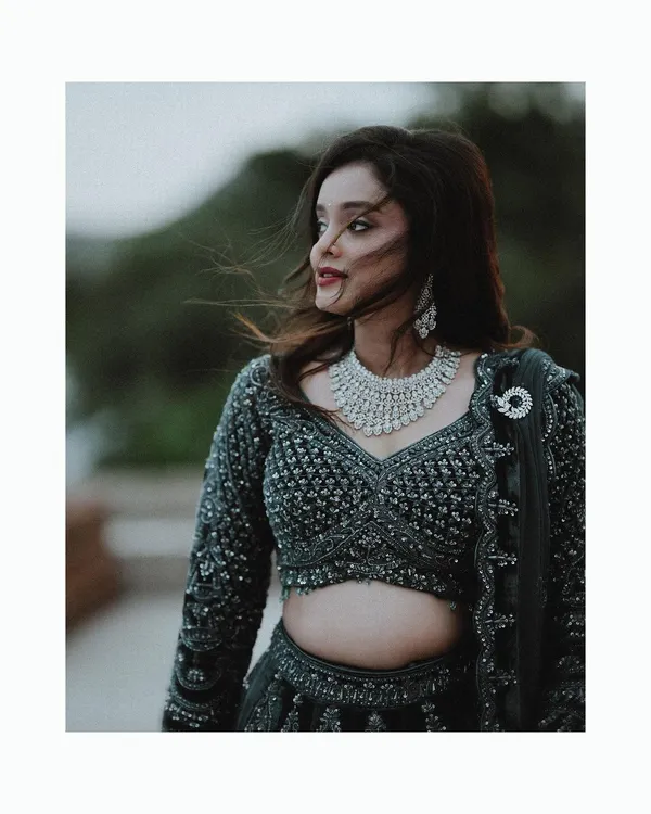 A stunning portrait of the bride with her hair blowing in the wind, showcasing her beautiful diamond necklace and elegant evening lehenga.