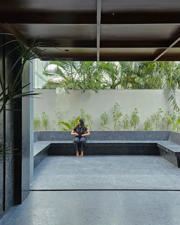 An open-air courtyard with built-in seating made from large slabs of black granite. This tranquil space is designed for employees to relax and recharge, surrounded by curated landscaping.