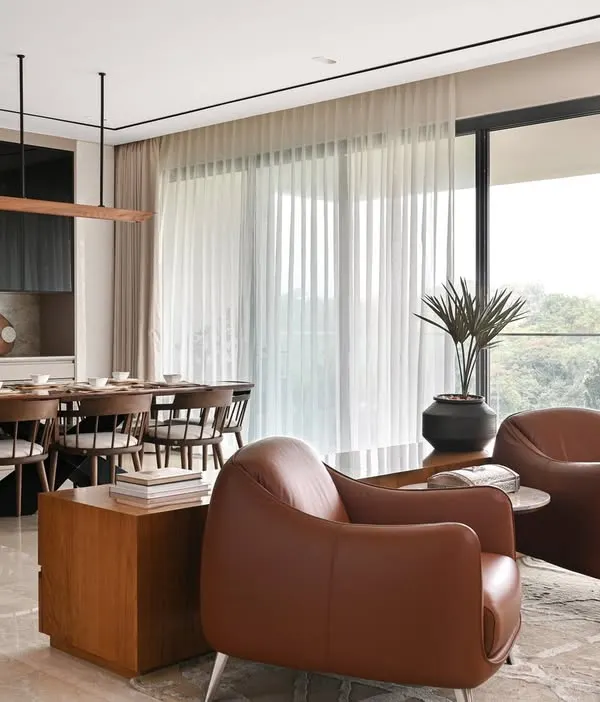 We designed this open-plan living and dining area to feel airy, warm, and welcoming. The large windows connect the space to the lush greenery outside, creating a sanctuary of laidback luxury in this Bengaluru apartment.
