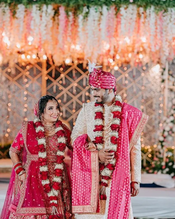 A surreal mandap designed with a cascade of suspended pink and white florals over a golden lattice backdrop. This is the kind of opulent and romantic setting I create for your main ceremony.