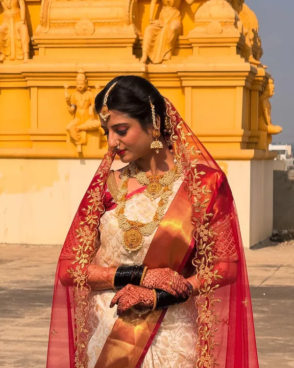 A demure and elegant bridal portrait. The sheer veil and traditional jewelry are perfectly complemented by makeup that highlights the bride's natural beauty for her wedding day.