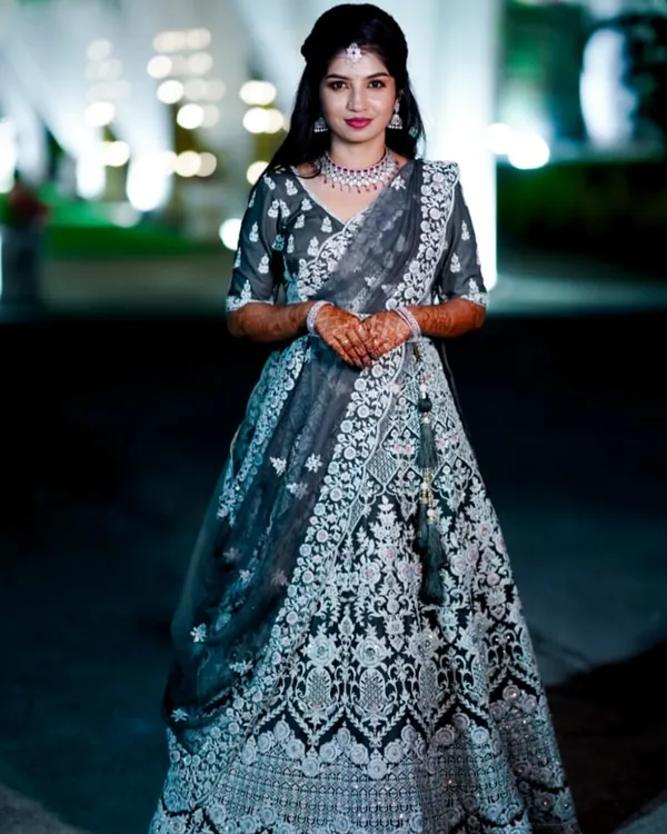 A full-length view of this stunning reception look. The makeup was designed to be elegant and photogenic, with a bold lip and defined eyes that stand out beautifully against the intricate silver embroidery of her lehenga.