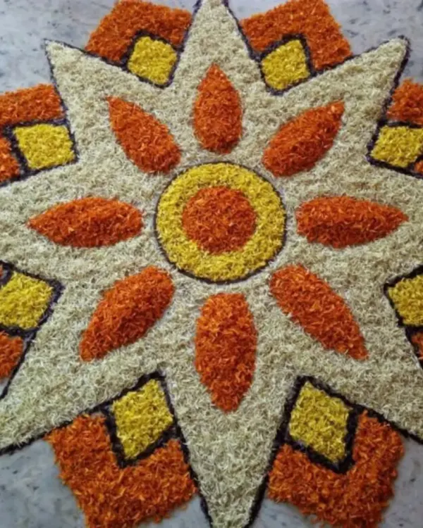 A star-shaped floral rangoli, or 'pookalam', made entirely from fresh flower petals. This kind of detailed work is perfect for welcoming guests at the entrance.