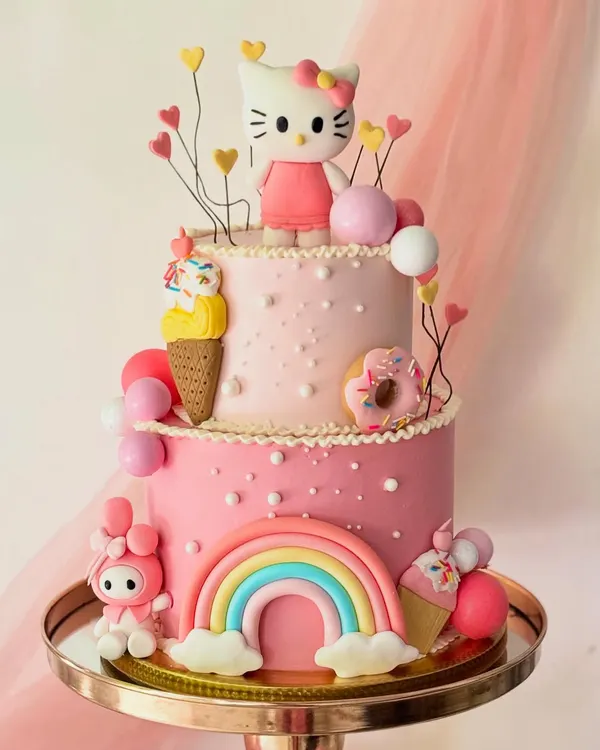 A two-tiered dream for a Hello Kitty fan, this cake is loaded with fun details. It features a Hello Kitty topper, a rainbow, donuts, and ice cream cones, all made from fondant on a pink buttercream base.