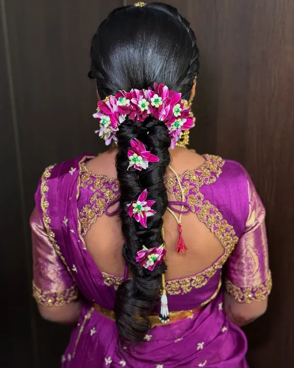A close-up of the stunning floral braid created for Saanvi's half saree ceremony. The vibrant pink flowers are woven into the braid, creating a beautiful and traditional look.